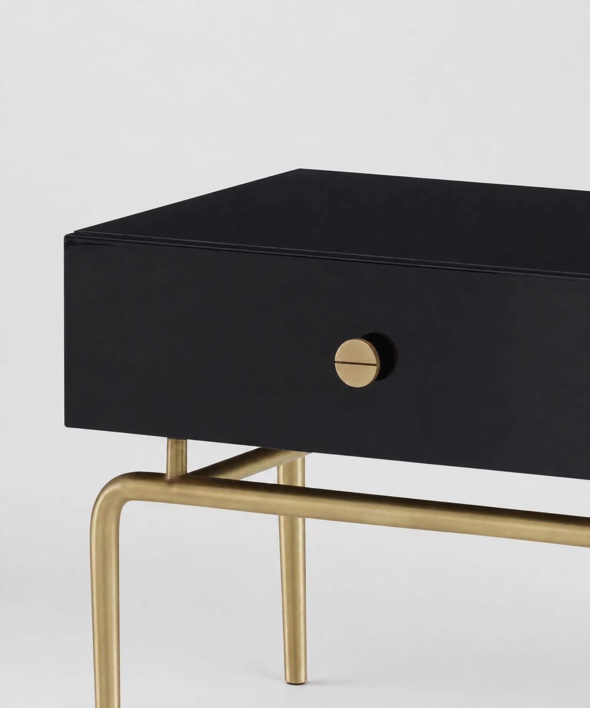 Ligne Roset Débourgeoisée consolle rettangolare con base in acciaio finitura ottonata spazzolata opaca cassettiera in MDF laccato nero brillante con due cassetti soft close vista in dettaglio su sfondo neutro