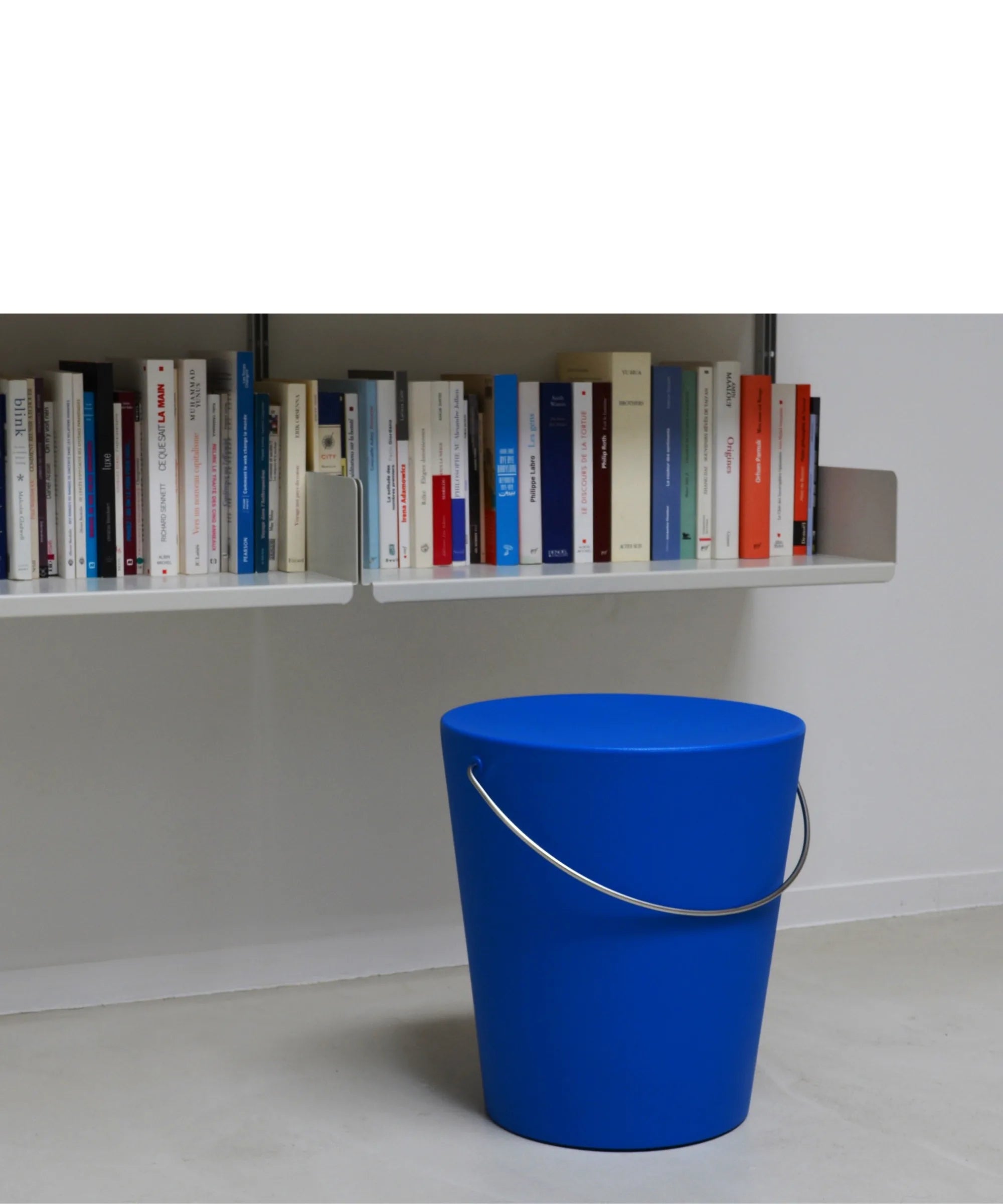 Sgabello Moving di Gabriele Pezzini blu ambientato in interno minimal con libreria