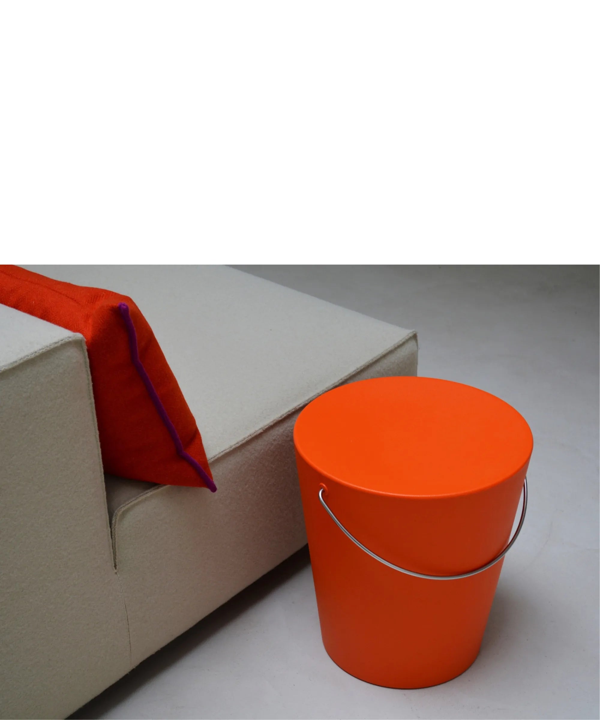 Sgabello Moving di Gabriele Pezzini arancione ambientato accanto a un divano contemporaneo